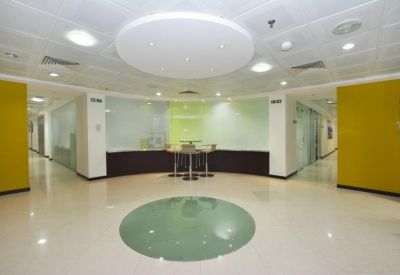 Open communal breakout area with a central high table and vibrant yellow accent walls.