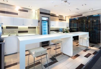 Bright communal kitchen area with a long white breakfast bar and tall stools.