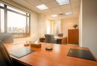 Bright executive office with a wooden meeting table, large windows, and built-in storage cabinetry.