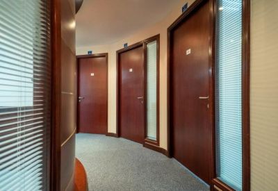Curved office corridor featuring dark wood doors and frosted glass side panels.