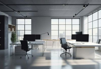 Open-plan workspace with multiple workstations, grey ceiling, and floor-to-ceiling windows.