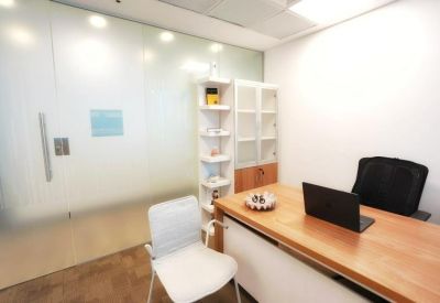 Modern workspace with a wooden desk, black office chair, and frosted glass wall.