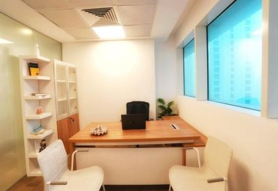 Two-person meeting setup with a wooden desk, white chairs, and city views through blue windows.