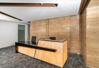 Professional reception desk with a sleek wood and black finish against marble-style wall panels.