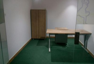 Private office suite with a wooden desk and matching wardrobe over green carpet.