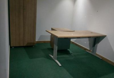 Sparse private office with a light wood desk and green flooring.