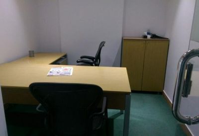 Small office space featuring a corner desk and two black ergonomic chairs.