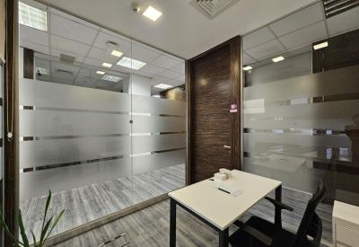 Meeting room with a white table, black chairs, and a wall-mounted screen.