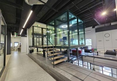 Industrial-style mezzanine lounge with a glass-walled office floating above the main floor.
