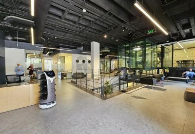 Spacious reception area with a modern desk, robot assistant, and industrial black ceiling.