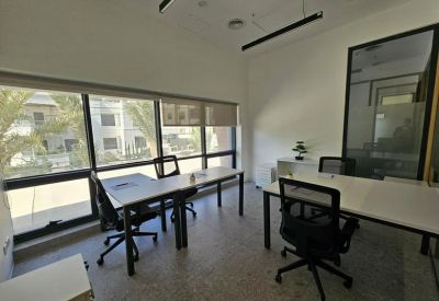 Private two-person office with grey desks, black chairs, and a large window overlooking the street.
