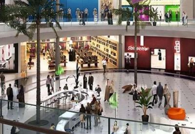 Spacious multi-level shopping and office atrium with palm trees and modern storefronts.