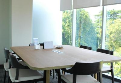 Bright conference room with floor-to-ceiling windows overlooking lush green trees.