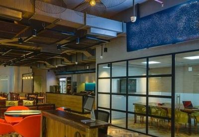 Glass-walled conference room adjacent to a colorful lounge area with orange seating.