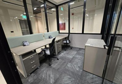Internal two-person glass-walled office suite with grey ergonomic chairs and patterned carpet.