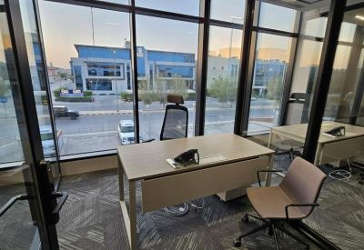 Private corner office featuring a sleek desk and floor-to-ceiling windows with a city view.