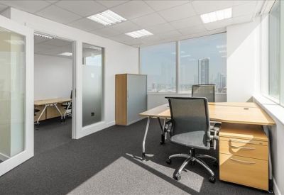 Bright corner office with city views and a light wood workstation.