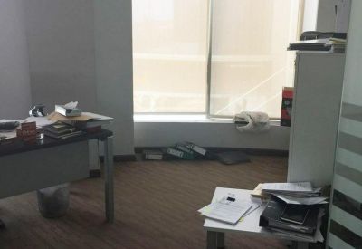 Bright office space with wood-style flooring and natural light from a large window.