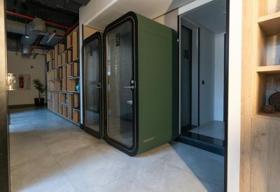 Hallway featuring soundproof green privacy pods for individual phone calls.