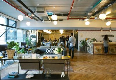 Spacious communal lounge with diverse seating, indoor plants, and warm wood flooring.