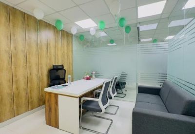 Bright office space with green balloons and a grey lounge sofa for guests.