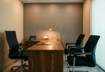 Professional three-person office with dark wood desk and warm task lighting.