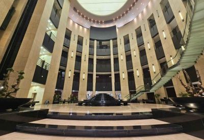 Grand circular atrium with architectural lighting and a sweeping glass staircase.
