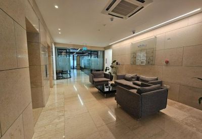 Spacious reception lounge with stone walls and grey armchairs.