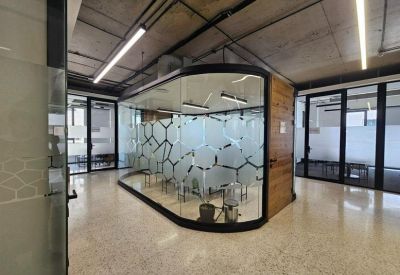 Modern open-plan office area with a distinctive curved glass meeting pod.