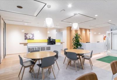 Communal breakout area with round wooden tables and modern lighting.