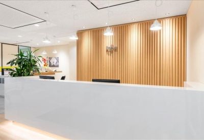 Bright white reception desk in front of a light wood-paneled wall.
