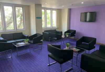 Vibrant communal lounge area with purple carpeting and modern black seating.