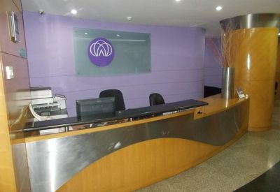 Wooden reception desk with a circular logo on a lavender feature wall.
