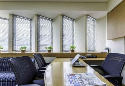 Private office featuring wooden desks, black ergonomic chairs, and large bright windows.