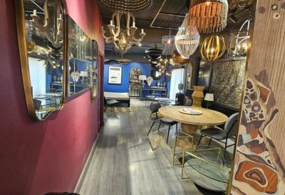 Long hallway featuring ornate mirrors, a round wooden dining table, and various light fixtures.
