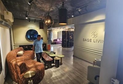 Branded reception area with a patterned brown curved sofa and 'SAGE LIVING' wall signage.