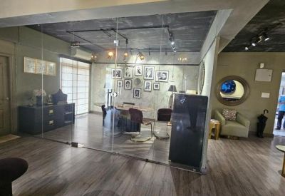 Office area behind a glass wall featuring a desk, chairs, and a gallery wall of framed art.