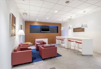 Lounge area with red leather armchairs and a large TV mounted on a wood-paneled wall.