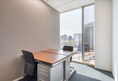 Private corner office with two desks and a large window overlooking the city skyline.