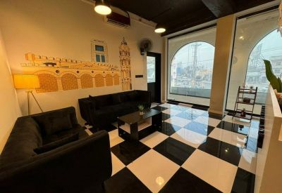 Modern lounge area with a black and white checkered floor, leather sofas, and an arched window.