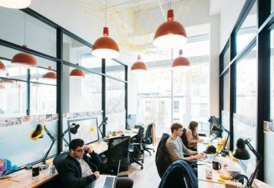 Bright open-plan workspace with rows of desks and modern red pendant lighting.