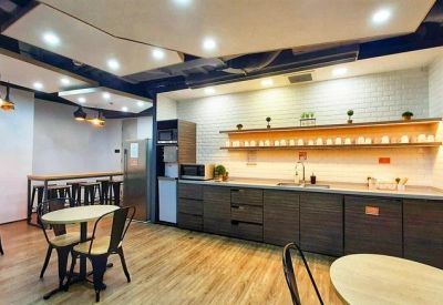 Modern office kitchen and dining area with wooden cabinetry and a sleek breakfast bar.