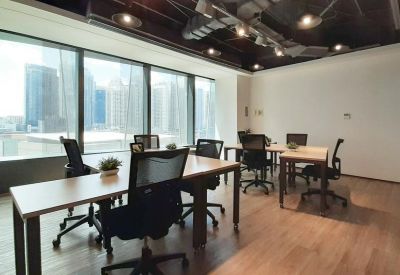 Bright open-plan office with multiple desks facing large windows overlooking the city.