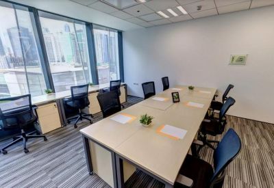 A long meeting table in a sunlit room with black mesh chairs and city views.