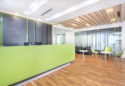 Vibrant lime green reception desk with a contemporary lounge and wooden flooring.