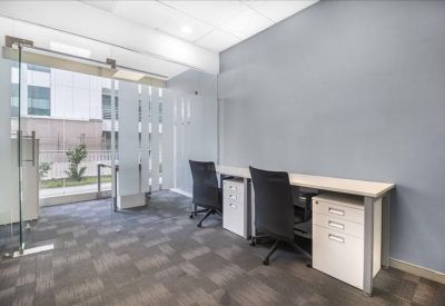 Bright two-person office suite with glass partitions and grey carpet.