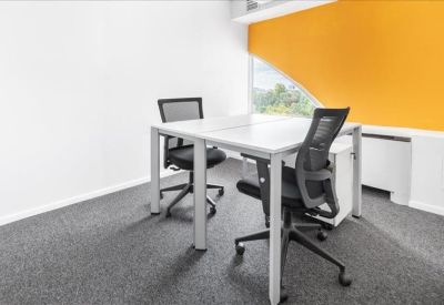 Private two-person office with white desks and a vibrant yellow feature wall.