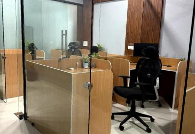 Modern office cubicles separated by glass walls and light wood paneling.