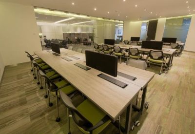 Open-plan coworking space with long wooden desks and ergonomic lime green chairs.