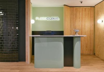 Sleek reception desk with a backlit logo set against a light green feature wall.